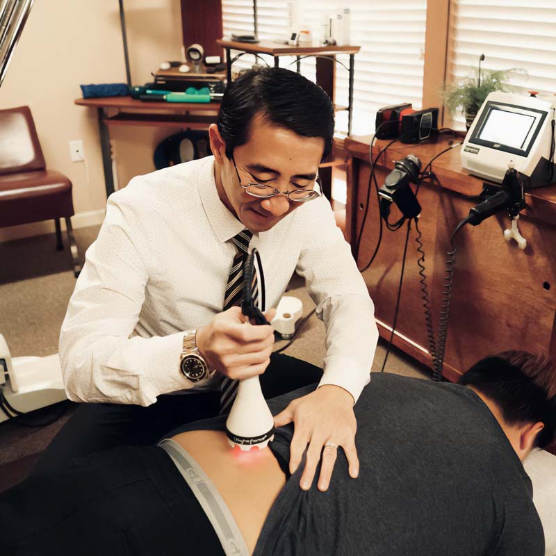 Dr. Dinh Le using a device for deep tissue laser therapy